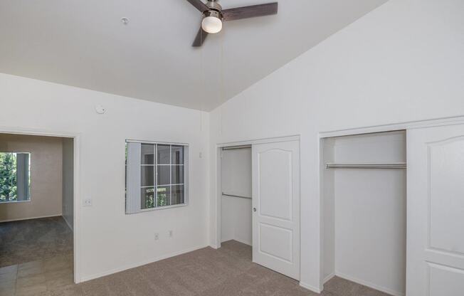 a living room with white walls and a ceiling fan