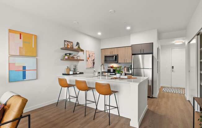 A modern kitchen with a white island and bar stools.