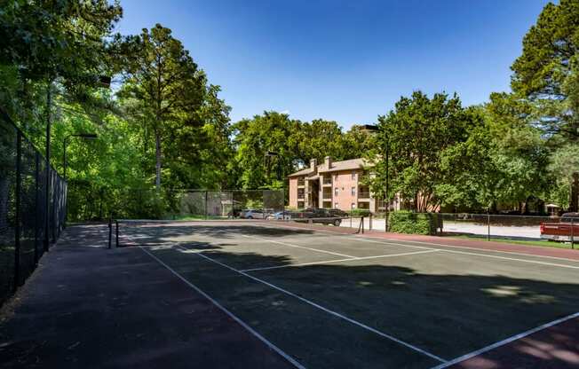 a tennis court with a building in the background at The Summit Apartments, Tennessee