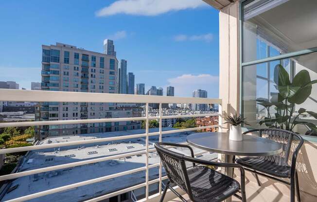 A balcony with a table and chairs overlooking a cityscape.