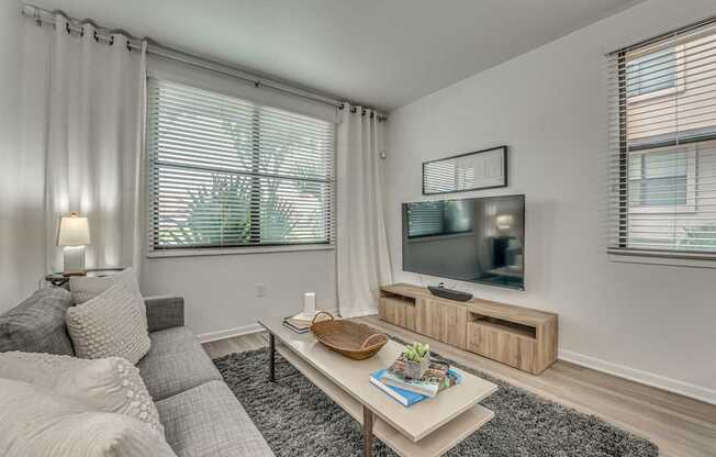 A living room with a grey couch, a white coffee table, and a flat screen TV.