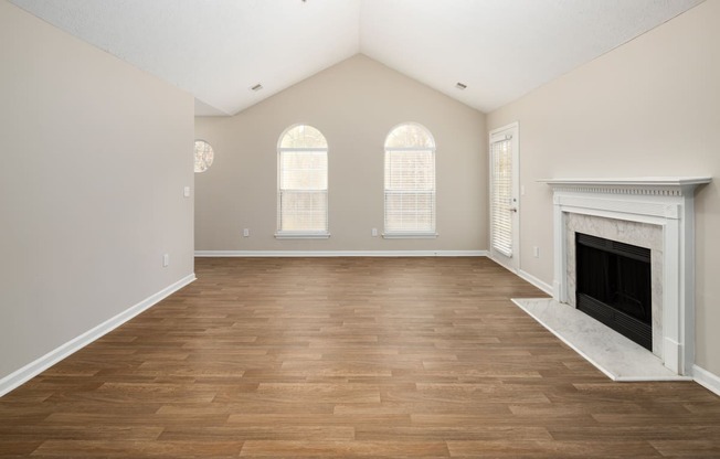 an empty living room with a fireplace and wooden floors