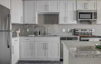 a kitchen with white cabinets and granite counter tops