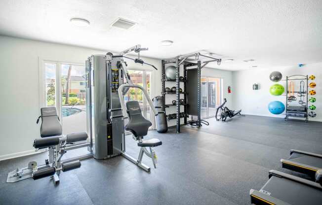 a gym with weights and cardio equipment on the floor and windows