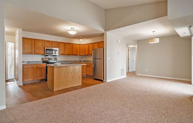 an empty kitchen with wooden cabinets and a stainless steel refrigerator