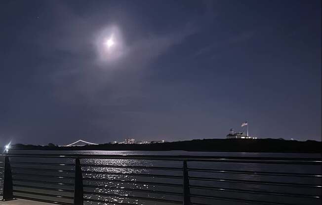 A bright light is shining in the sky over a body of water.