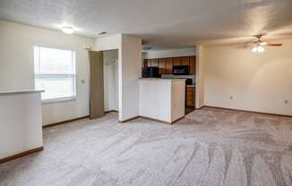 an empty living room and kitchen with a ceiling fan