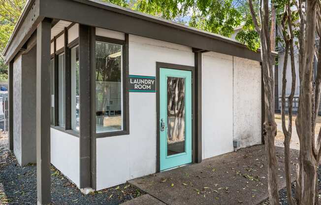 a white building with a green door and a sign that reads laundry room