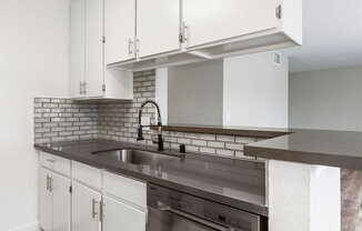 White tiled kitchen with stainless steel fixtures.