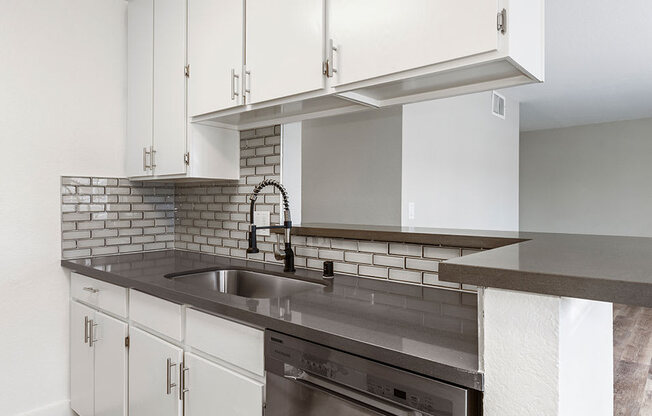 White tiled kitchen with stainless steel fixtures.