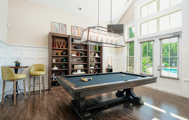 a pool table in a living room with a light hanging over it