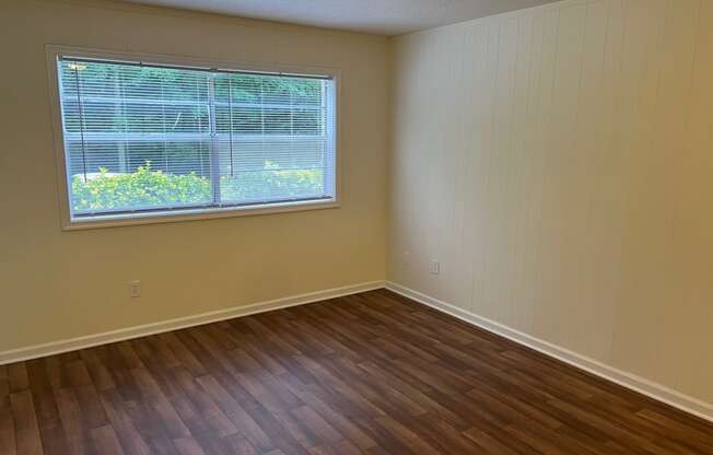 an empty living room with wood floors and a window