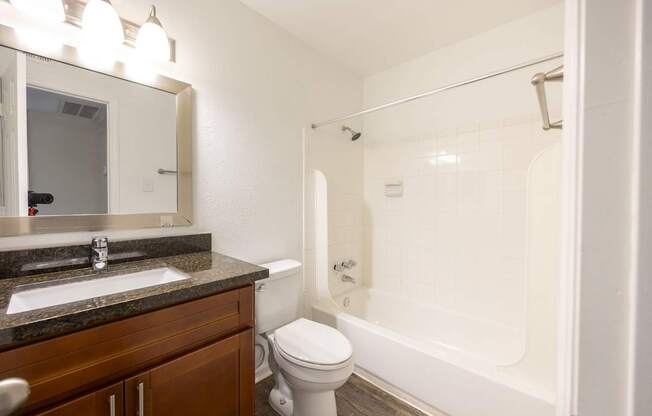 A white toilet sits in a bathroom next to a sink and a bathtub.