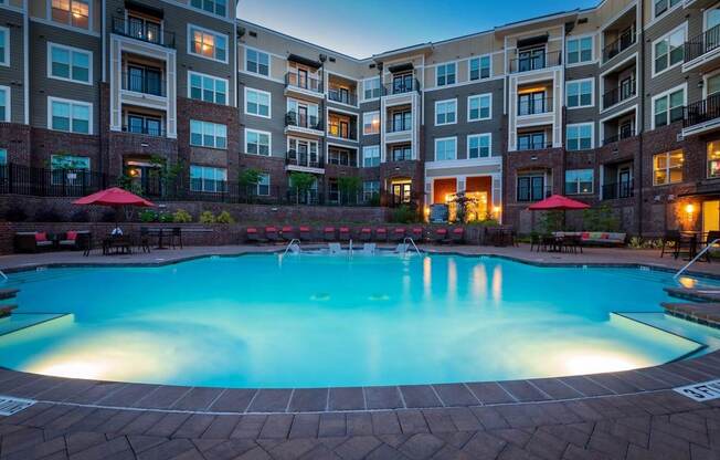 A swimming pool in front of a multi-story apartment building.