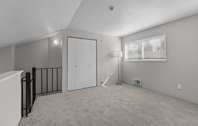 the living room of an apartment with a staircase and a window