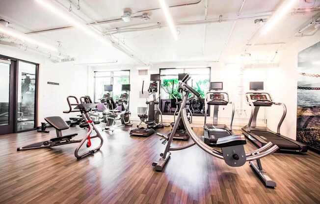 A gym with a variety of equipment including treadmills, stationary bikes, and weight machines.