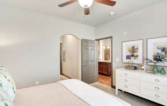 a bedroom with a white bed and a ceiling fan