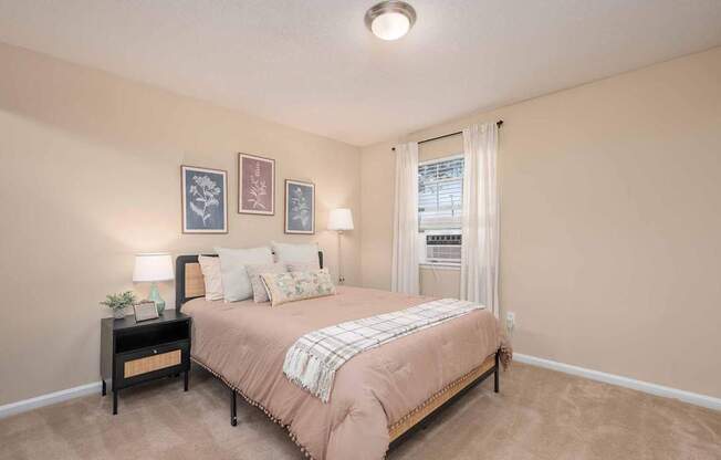 A bedroom with a bed, nightstand, and pictures on the wall.