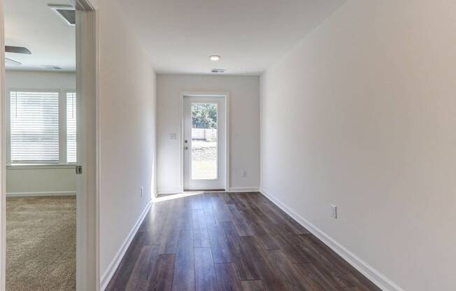 a living room with white walls and wood flooring and a door
