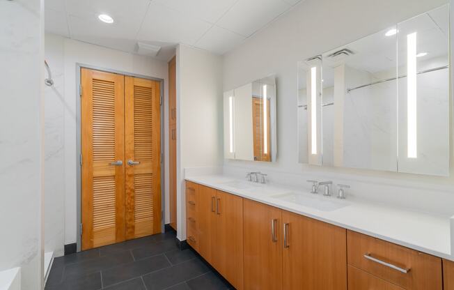 a bathroom with two sinks and a shower and wooden doors