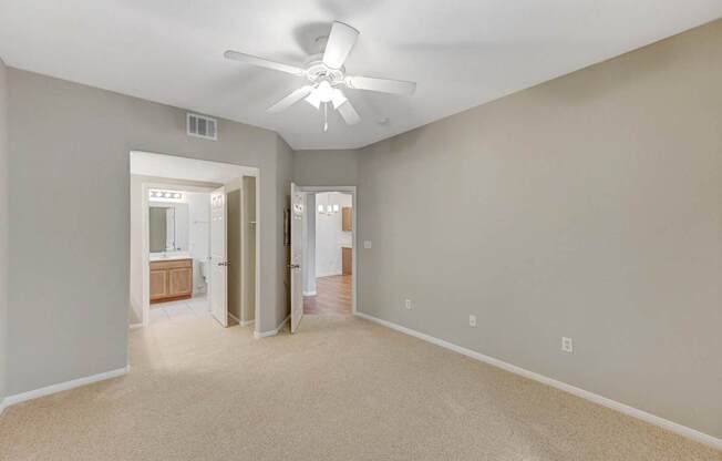 A room with a ceiling fan and carpeted floor.