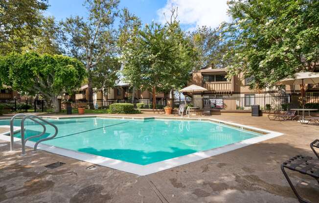 a swimming pool with trees and a building in the background