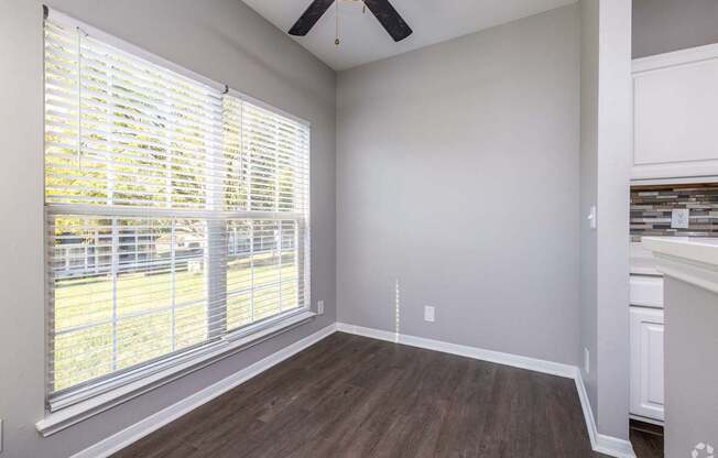 A room with a window covered by white blinds and a ceiling fan.