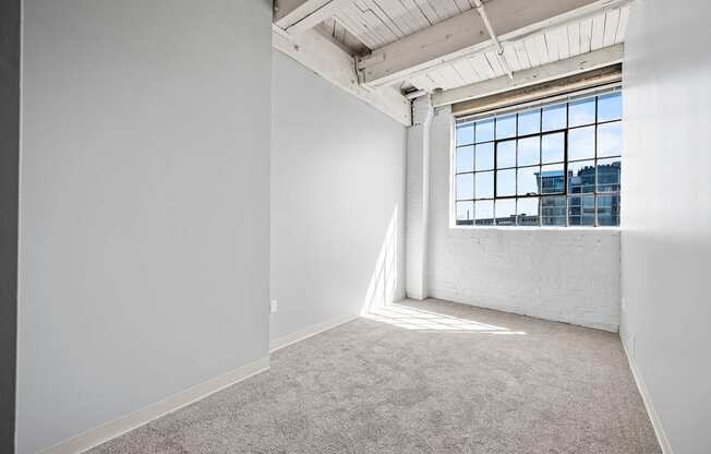 A large empty room with a window overlooking a cityscape.