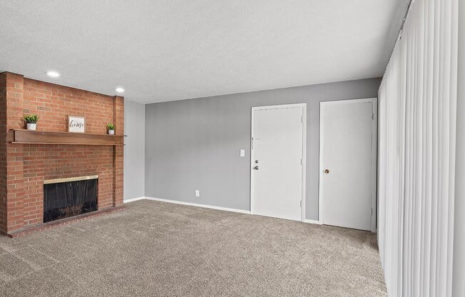 an empty living room with a brick fireplace and white doors