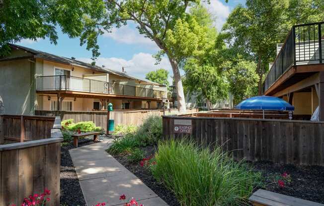 View in between buildings showcasing lush landscaping with sidewalk in between buildings and private patio/balcony