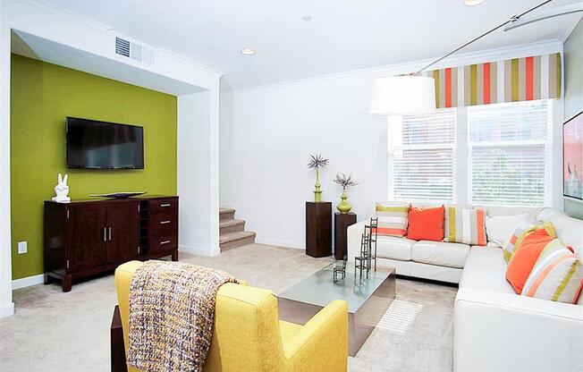 A living room with a yellow chair and a glass coffee table.