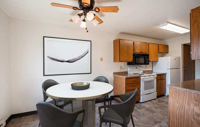 a kitchen and dining area with a table and chairs and a ceiling fan. Fargo, ND Southview Village Apartments
