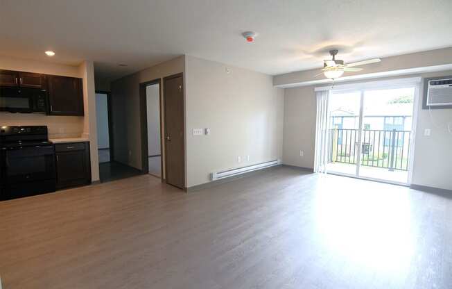 an empty living room with wood flooring and a balcony