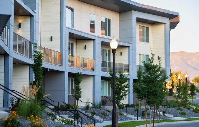 A modern apartment building with balconies and flower beds in front.