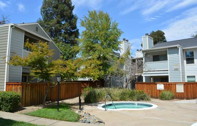 View of community spa, lush shrubbery, private patio/ balcony and exterior of buildings
