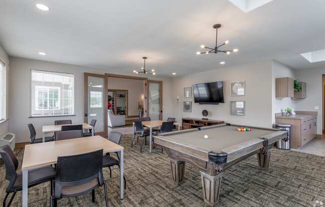 a community room with a pool table and chairs and a tv