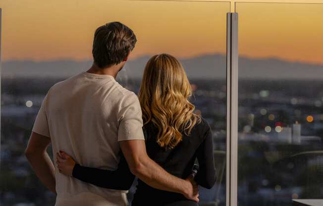 a man and woman looking out of a window overlooking the city at sunsetat AVE Phoenix Sky, Phoenix, 85003