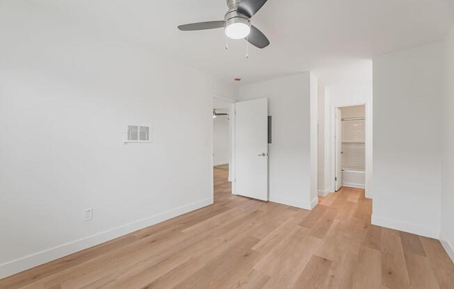 A room with a ceiling fan and wooden flooring.