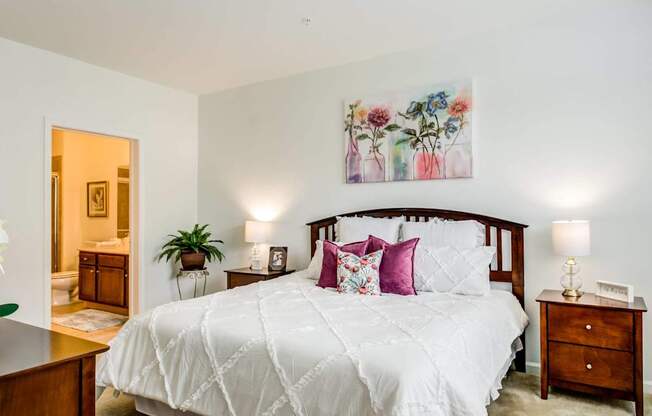 A bedroom with a large bed and a painting above it.