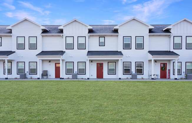 A row of white houses with red doors.