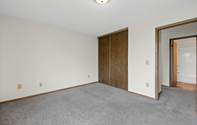 A room with a grey carpet and a wooden door.