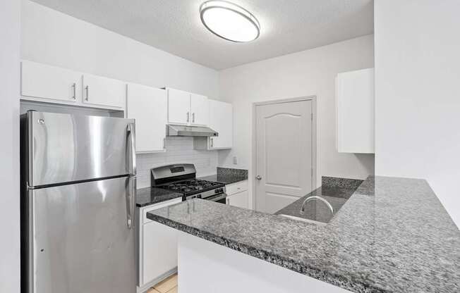 A kitchen with a granite countertop and stainless steel appliances.