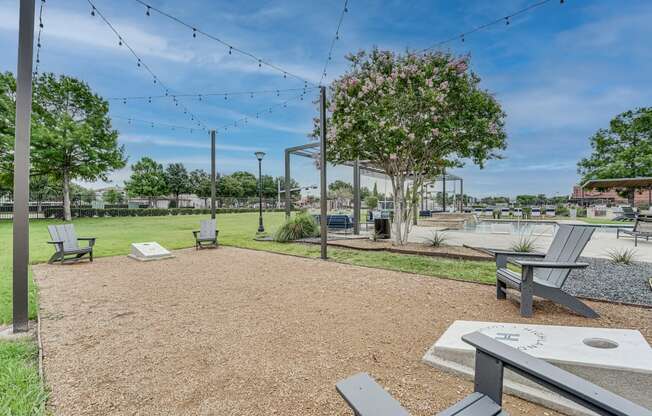 a park with benches and a grassy area with a sprinkler system in the background