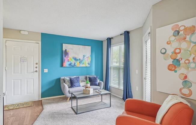 A living room with a blue wall and a painting on it at The Falls Apartments in Raleigh NC