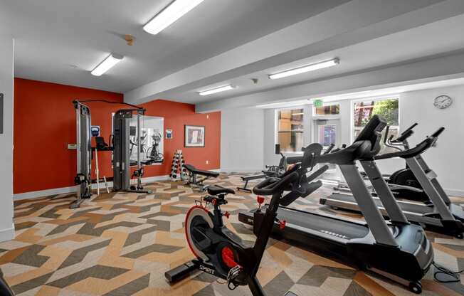 a gym with treadmills and other exercise equipment in a room with red walls