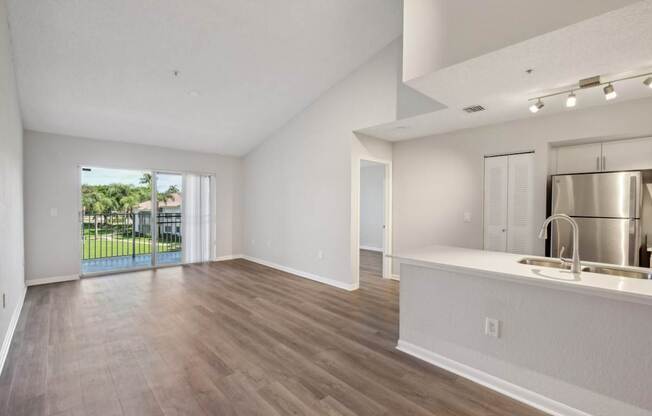 A spacious kitchen with a sink and a window overlooking a green area.