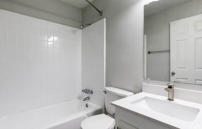 A white bathroom with a tub, toilet, and sink.