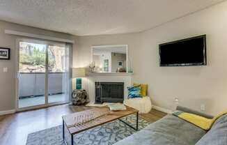 A living room with a fireplace and a flat screen TV mounted on the wall.