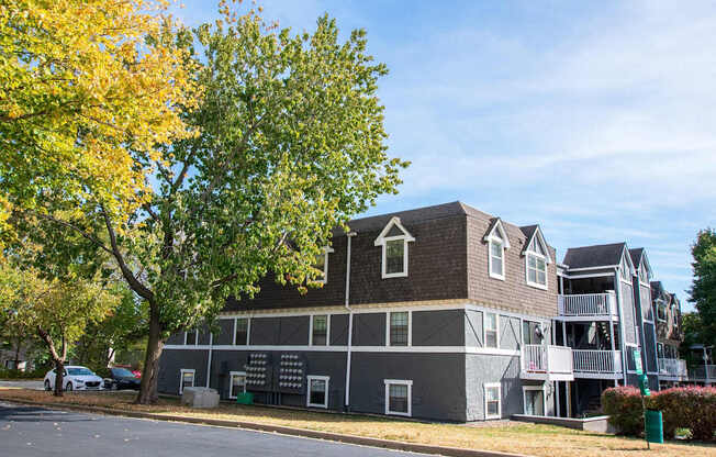 A large grey building with a tree in front of it.