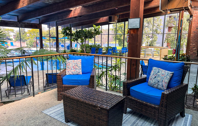 A patio with blue chairs and a wicker table.